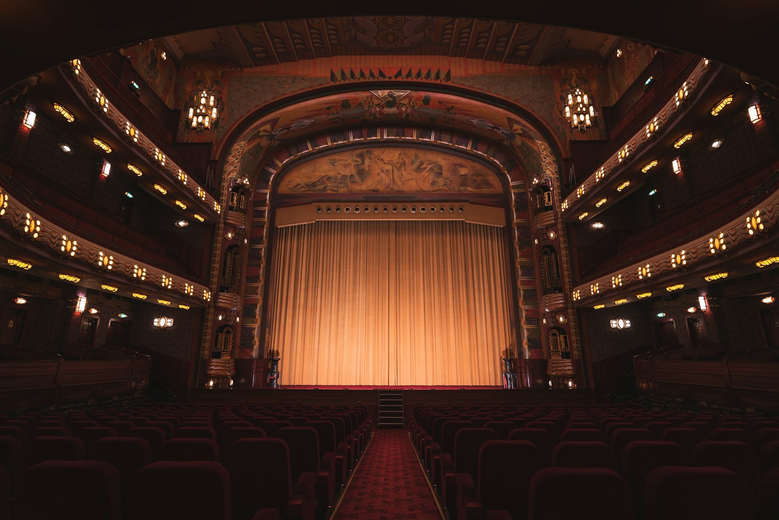 Illustrative auditorium with a centered stage, warm golden lighting and burgundy seating; not bergenPAC