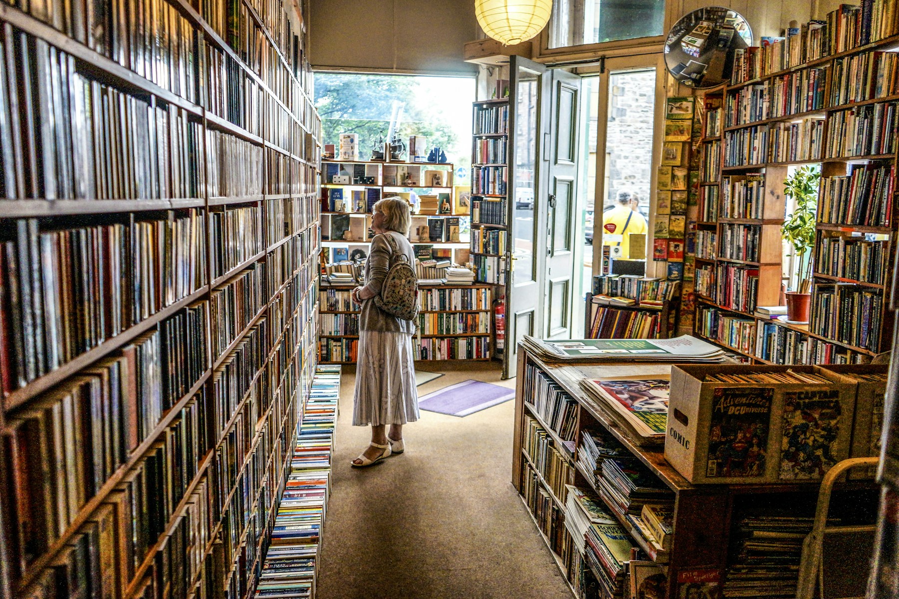 Illustrative bookstore interior with wooden bookshelves and a browsing customer; not Bookends
