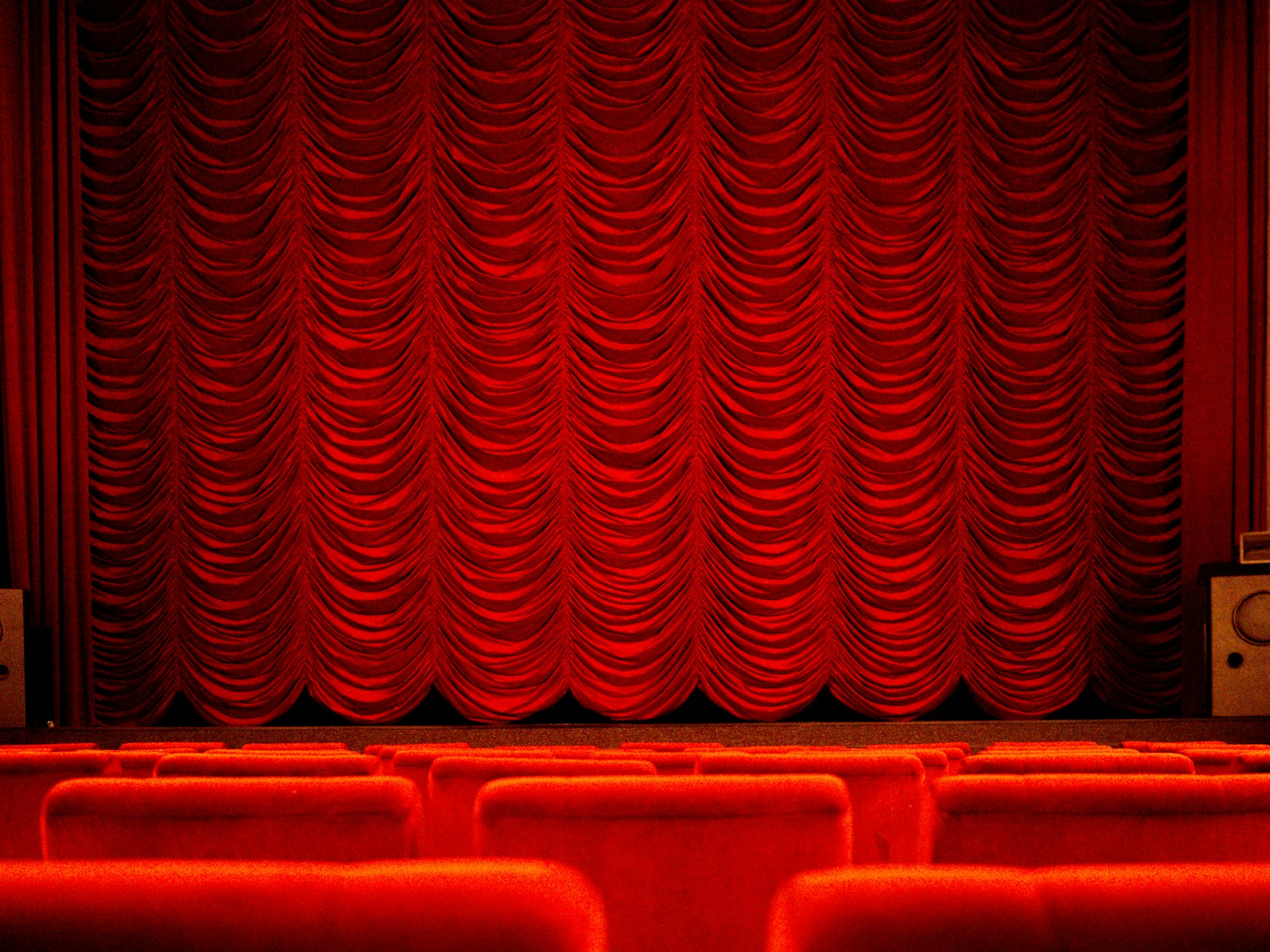 Illustrative theater with scalloped red curtains and red seats; not Little Firehouse Theatre